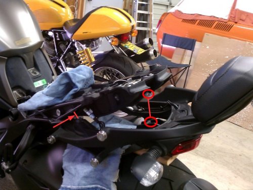 Removing the pillion backrest and grab handles is very easy.  There are only three, 6mm bolts.  One under the seat on each side (red arrow) and the other one is below the back rest mount, center-line of the seat.  Be careful when lowering it due to all the wiring.  I would also recommend covering the rear fender to protect both pieces from being scratched.
