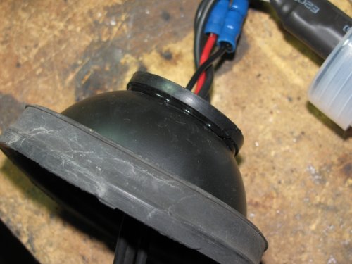 With the rubber cover turned inside-out, lift up the gasket and apply a continuous bead of silicone sealant a.k.a. RTV.  This will insure a water-tight seal.  Return the boot to its original state.
