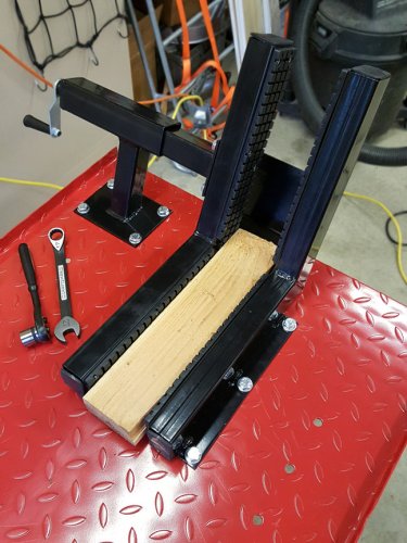 Due to some minor slop in vise, gently press an object in the vise (I used a 2x4) and then tighten the bolts in a star pattern.

While the clamp could be mounted the other direction it would likely interfere with a bike that has deep fenders.  Also, the clamp would need to be opened more to allow the axle, calipers, and axle sliders past.
