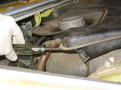 Remove the 10mm bolt from the rear, right side of the expansion tank. Note that in this picture the drain hose has been disconnected. 
